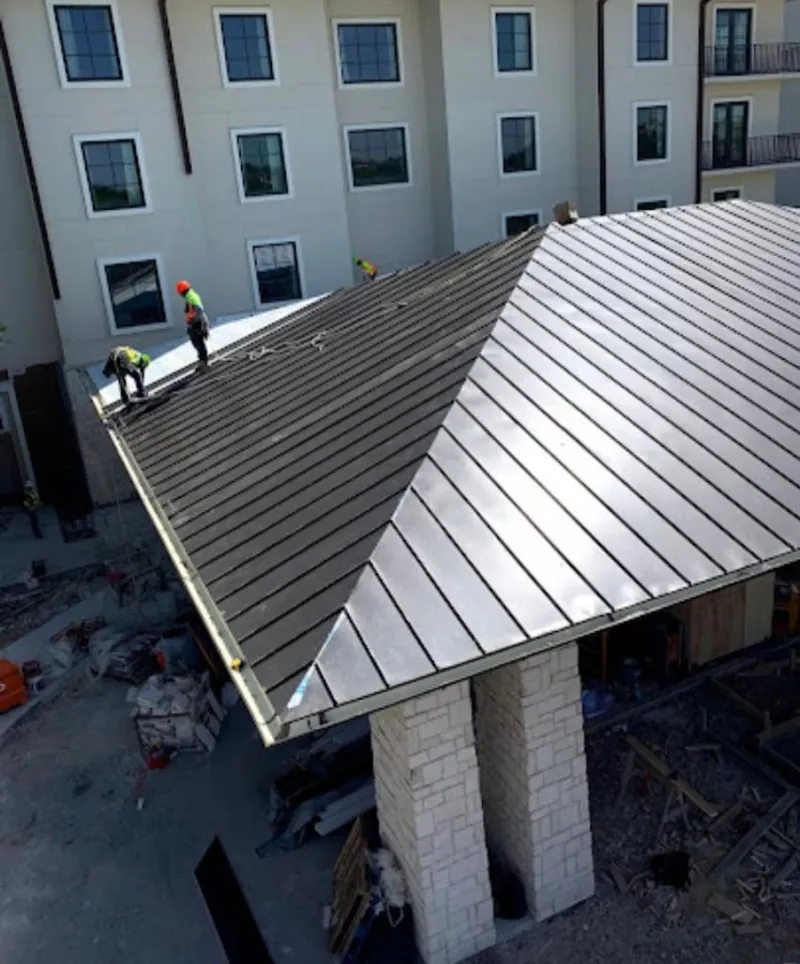 Crew installing standing seam metal roof panels on a commercial project in Englewood